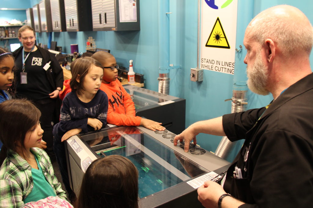 Seiji and other children learning about laser cutting at the Museum of Science and Industry's Fab Lab.